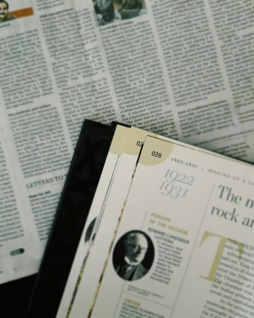 A corner of a page of a magazine lying over a newspaper.